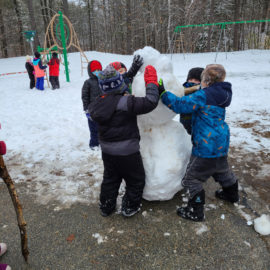 Featured image of article: Working together to build a snowman!